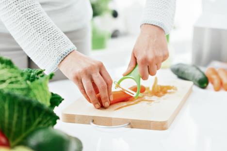 stockphotowomancookinghealthyfoodinherkitchensheispeelingfreshrawcarrotsonachoppingboard588853280.jpg