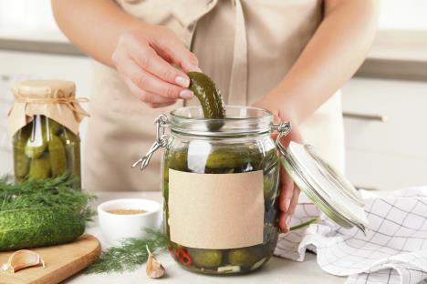 stockphotowomantakingpickledcucumberfromjarattableinkitchencloseupviewspacefortext1496457209.jpg