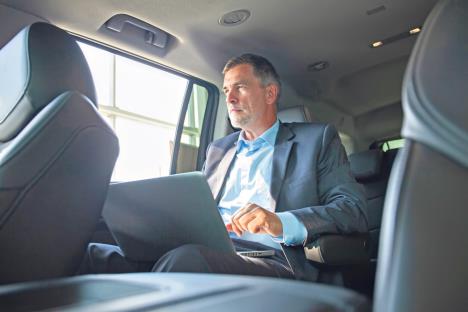 1004-stockphotohandsomebusinessmansittingwithlaptoponthebackseatofthecarcaucasianmalebusiness1159947400.jpg