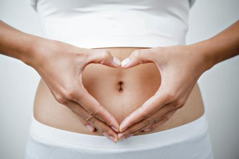 stockphotocloseupofwomanshandsmadeheartonbellyisolatedonwhitebackgroundhealthcareconcept583399804.jpg