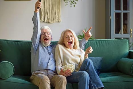 stockphotoexcitedhappyoldcouplefootballfansholdingremotecontrolwatchingsporttvgamecelebrategoal1437576926.jpg