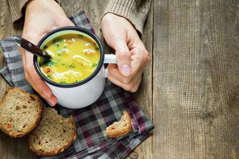 stockphotowomanhandsholdingmugofvegetablesoupwithparsleyandcroutonsoverwoodenbackground562910662.jpg