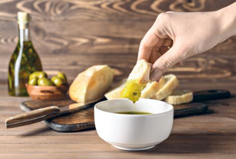 stockphotowomandippingfreshbreadintotastyoliveoilinbowl1370793509.jpg