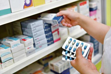 stockphotopharmacistholdingmedicineboxandcapsulepackinpharmacydrugstore717437125.jpg