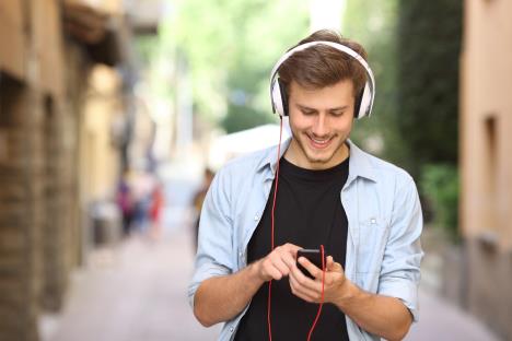 frraj-stockphotohappyguywalkingandusingasmartphonetolistenmusicwithheadphones279713771.jpg