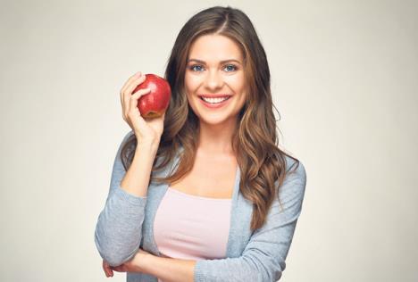 stockphotosmilingwomanwithhealthyteethholdingredapplestudioisolatedportrait522521242.jpg