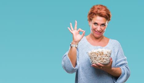 stockphotoatrractiveseniorcaucasianredheadwomaneatingpopcornoverisolatedbackgrounddoingoksign1217564032-1563-900.jpg