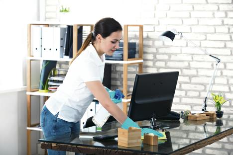 stockphotohappyyoungwomancleaningtheglassofficedeskwithrag673634095.jpg