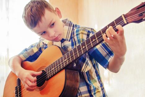 stockphotoboylearningtoplaytheacousticguitarinablueshirtconcentrationonplayingthemusic569998930-17-03-2020.jpg