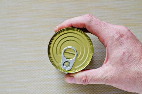 stockphotohandofanadultmanholdsacanofcannedfoodclosedtincanwithopenkeyinhandamanshand1665506377.jpg