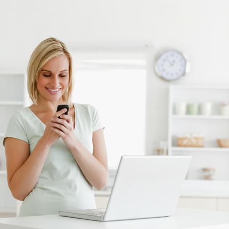 stockphotocutewomanwithmobileandlaptopsmilinginthekitchen81722635.jpg