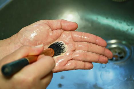 stockphotowomanmustcleaningmakeupbrushesisimportantswirlthebrushinyourpalm653615041.jpg