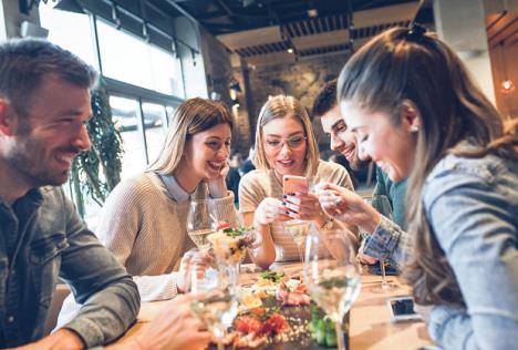 stockphotogroupofyoungfriendshavingfuninrestauranttalkingandlaughingwhilediningattable1557632120.jpg