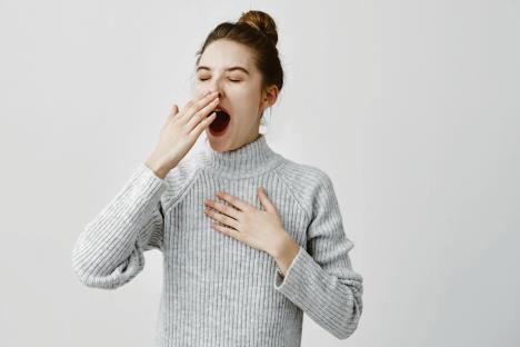 stockphototiredwomanyawningcoveringopenmouthwithhandneedrestyoungfemaleworkerbeingsleepyhead763023466.jpg