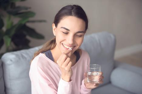 stockphotoyounghappysmilingmixedracewomansittingonasofaatlivingroomholdingglassofpurewater1477334273.jpg