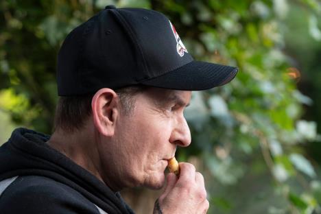 Čarli Šin u duksu sa kačketom na glavi