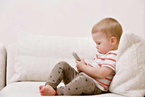 1001-stockphotoadorabletoddlerboysittingonthesofainthelivingroomandplayingwithsmartphonechild544329514.jpg