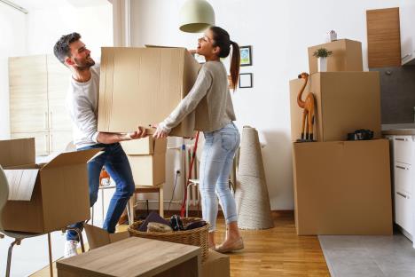 stockphotoyoungcouplecarryingbigcardboardboxatnewhomemovinghouse568241401.jpg