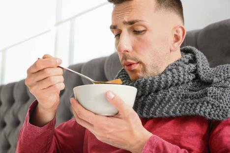 stockphotosickyoungmaneatingbrothtocurecoldinbedathome1089449501.jpg