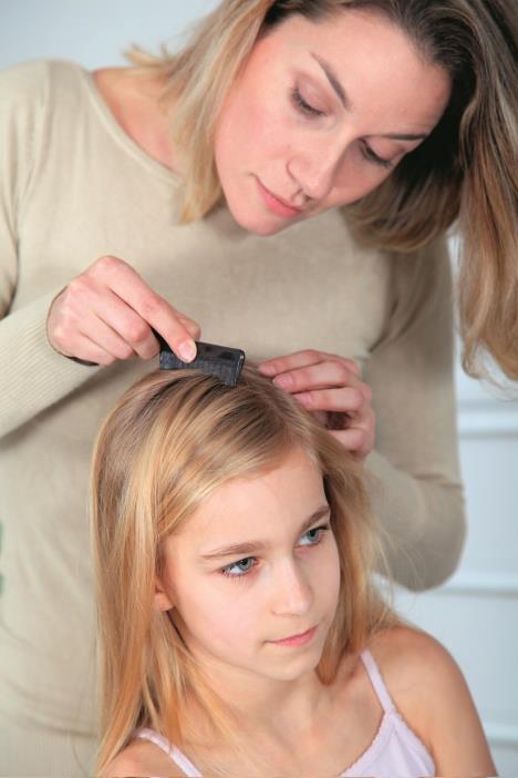 Majka gleda kosu devojčice koja ima vaške