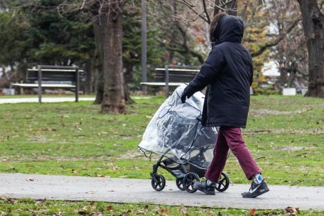 Žena gura dečja kolica u parku