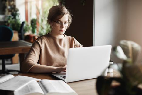 worklifestylebusinessconceptgoodlookingfocusedeuropeanfemaletrendyglassessittingcafenearlaptopworkingnotebooksurroundedwithbooksmakingnotes.jpg