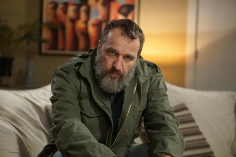 Nenad Jezdić u zelenoj jakni sedi na kauču
