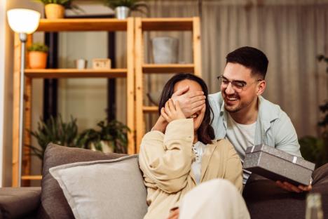 Muškarac pokrio ženi oči i drži poklon