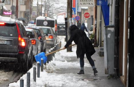 Žena čisti sneg lopatom