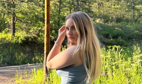 Devojka plave kose stavlja pramen iza uha