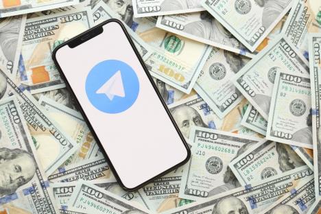 Mobilni telefon sa Telegram aplikacijom na novcu