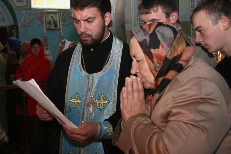 Baka se skrštenih ruku moli dok sveštenik čita molitvu