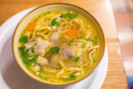 Činija domaće supe sa mesom i rezancima stoji na stolu