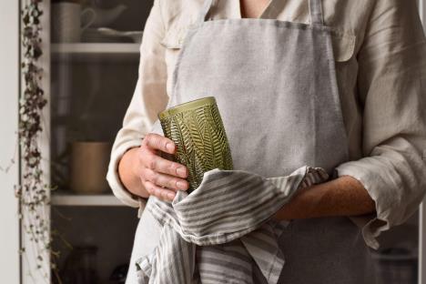 Osoba briše čašu kuhinjskom krpom