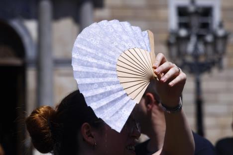 Žena se lepezom štiti od sunca