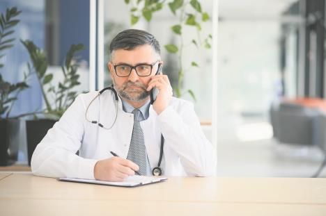 Doktor u kancelariji priča na mobilni telefon