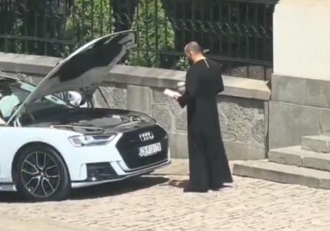 Sveštenik u crnoj mantiji drži otvoren molitvenik ispred Audija