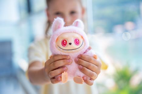 Devojčica drži rozog Labubua u rukama