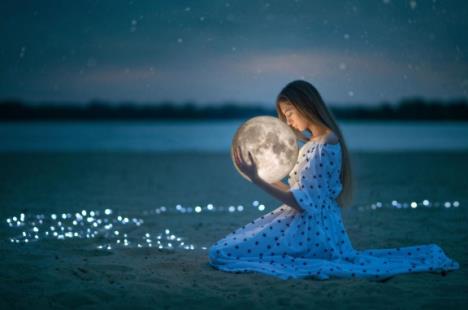 Devojka u haljini na tufne kleči na pesku i grli pun Mesec