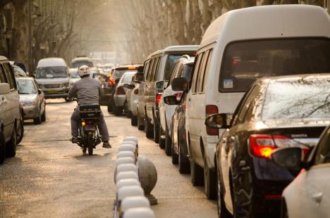 Motociklista prolazi pored kolone automobila