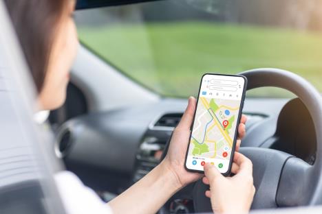 žena u kolima gleda u telefon i prati mapu, koncept GPS