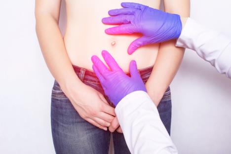 Doktor opipava stopak žene sa akcentom na pupak