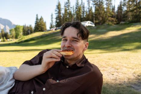 Muškarac jede picu u prirodi