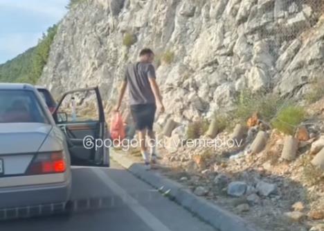 Čovek skuplja smeće dok čeka kolima na granici