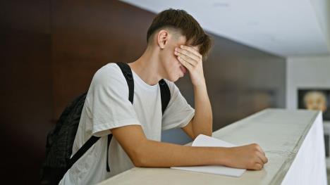 Mladić se drži za glavu, a drugom rukom drži svesku