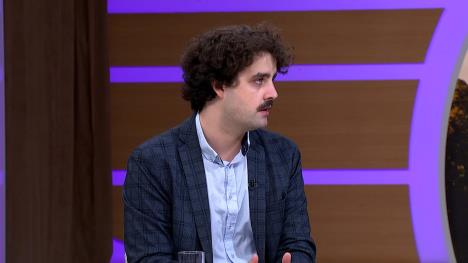 Mladi muškarac sa brkovima i kovrdžavom kosom u televizijskom studiju