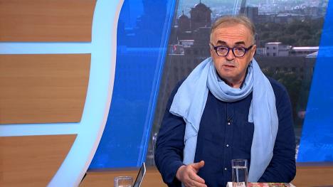 Muškarac sa plavom košuljom i svetlo plavim šalom u televizijskom studiju