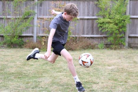 Dečak u dvorištu igra fudbal