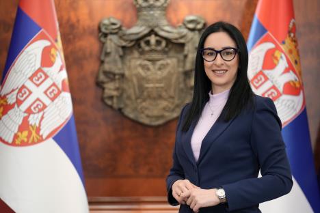 Ministarka Jelena Žarić Kovačević pored srpske zastave i grba