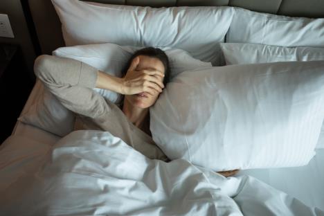 Devojka leži u krevetu sa šakom na očima